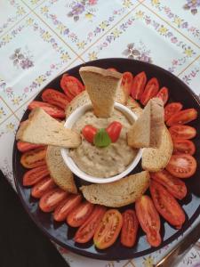 a plate with a bowl of hummus and crackers and hot dogs at Apartman egy Makovecz Imre tervezte házban in Ispánk