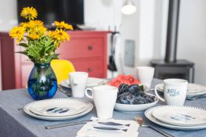 una mesa con platos y tazas y un jarrón con flores en Pomeranka Domki Ustka en Ustka