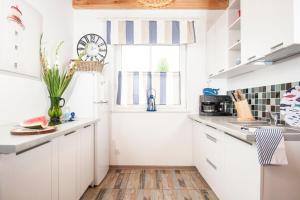 a kitchen with white cabinets and a window at Pomeranka Domki Ustka in Ustka