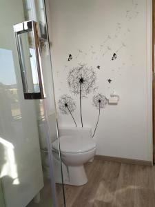 een badkamer met een toilet met paardenbloemen en vlinders aan de muur bij Chalet du Spièmont in Champdray