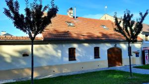 ein weißes Gebäude mit brauner Tür und zwei Bäumen in der Unterkunft Penzion na Figleně in Slatinice