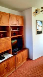 a living room with a television and wooden cabinets at Penzion na Figleně in Slatinice