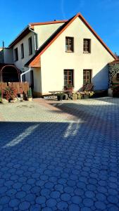 a large white house with a brick driveway at Penzion na Figleně in Slatinice