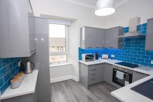 a kitchen with blue tiles on the wall at The Warwick Apartment in Greenock