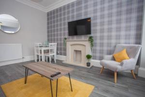 a living room with a tv and a chair and a table at The Warwick Apartment in Greenock
