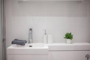 a white bathroom with two sinks and a plant on it at The Warwick Apartment in Greenock +9 photos