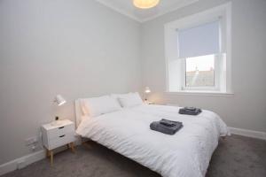 a white bedroom with a white bed and a window at The Warwick Apartment in Greenock