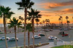 a parking lot with parked cars and palm trees at Steps To The Beach, Pacific City and Main Street - #5 in Huntington Beach