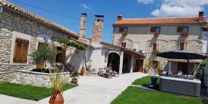 dom z patio i parasolem na dziedzińcu w obiekcie Rooms & Apartment STELIO w mieście Loborika
