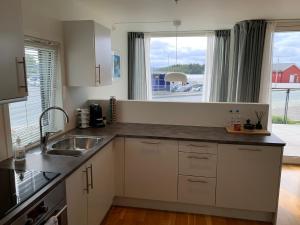 uma cozinha com um lavatório e uma grande janela em Modern apartment in the Harbour of Jørpeland em Jorpeland