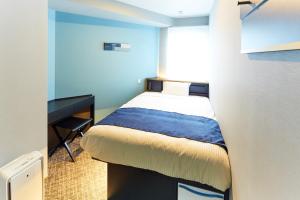 una piccola camera con letto e scrivania di ICI HOTEL Tokyo Hatchobori a Tokyo
