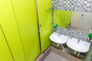 a green bathroom with two sinks and a mirror at Хостел 689CapsuleHotel&Coffee in Almaty