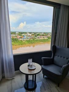 um quarto com uma cadeira, uma mesa e uma grande janela em Chaisaeng Palace Hotel em Sing Buri