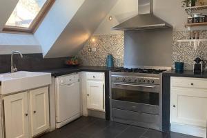 a kitchen with white cabinets and a stove and a sink at VENOSC Le Haut de la Grange in Les Deux Alpes