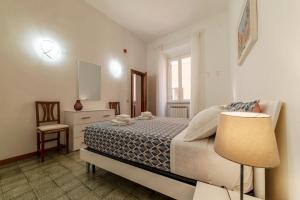 Un dormitorio con una cama con una lámpara y una silla. en Casa dell'Arco - WelcomeToRhome, en Roma