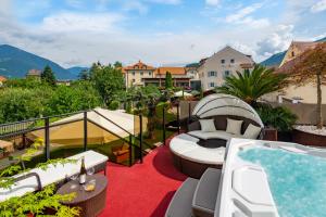 uma varanda com uma banheira de hidromassagem e uma sala de relaxamento em Hotel Traube em Bressanone