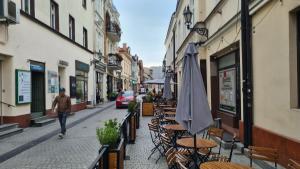 una persona caminando por una calle con mesas y sillas en Raciborska Royal Apartment - miejsce parkingowe na parkingu strzeżonym, en Gliwice