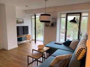 salon z niebieską kanapą i telewizorem w obiekcie Heimathafen Prora, 3.OG mit Meerblick w mieście Binz