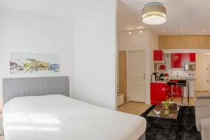 a bedroom with a white bed and a kitchen at Logement de charme - Saint Pierre - Cœur historique Bordeaux in Bordeaux +2 photos