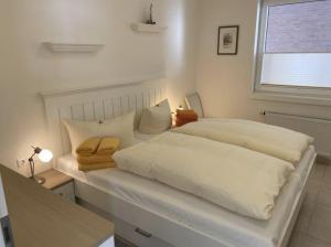 ein großes weißes Bett in einem Zimmer mit Fenster in der Unterkunft Norderneytraum Kampstr. Whg. 3 in Norderney
