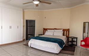 a bedroom with a large bed and a red chair at 15 @ Porter Guesthouse in Port Shepstone