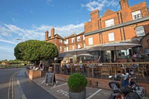 una motocicleta estacionada frente a un restaurante con sombrillas en The Bell Hotel, en Sandwich