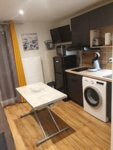 cocina con mesa y lavadora en Le 67,ski et randonnée,lave linge,sèche linge,parking, en Bernex