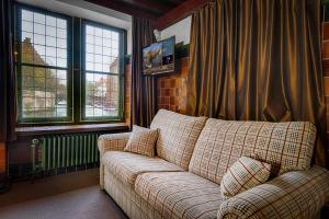 a couch sitting in a living room with windows at Hotel Bourgoensch Hof in Bruges