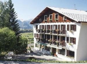 Un grand bâtiment blanc avec des plantes sur les balcons dans l'établissement La Bonne Auberge, à Risoul