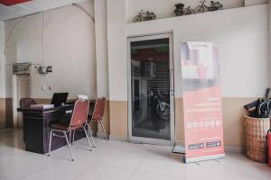 a room with a desk with a laptop and chairs at RedDoorz @ Jalan STM Medan in Medan