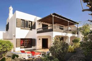 ein weißes Haus mit einem Balkon und einigen Stühlen in der Unterkunft Casa Jardin ideal para familias in Arrecife