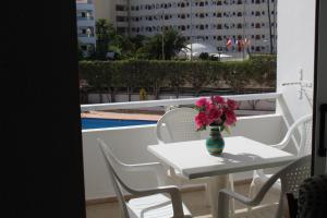 a table and chairs with a vase of flowers on a balcony at Farilaga Apartments in San Bartolomé