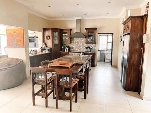 een keuken met een tafel met stoelen en een koelkast bij Elements Private Golf Reserve in Bela-Bela