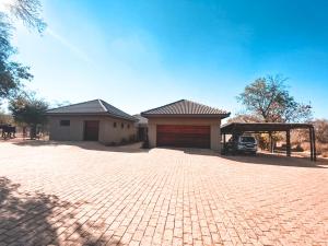 a house with a brick driveway in front of a garage at Elements Private Golf Reserve in Bela-Bela