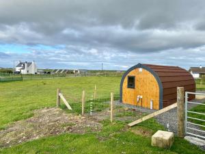 a barn in a field with a fence at Fuaim na Mara - Self Catering Pod in Creagorry