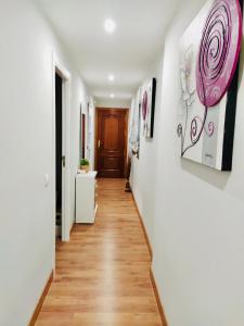 a hallway with white walls and wooden floors and paintings on the walls at Calma cañada in Talavera de la Reina