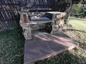 a stone fire pit with a bench on the grass at Linquenda Guest Farm in Lanseria