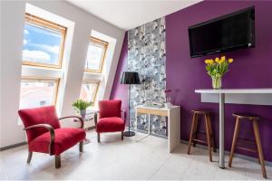 um quarto roxo com cadeiras e uma televisão na parede em Apartament Broadway em Poznań