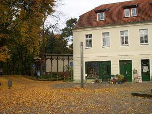 a white house with green doors in a parking lot at Ferienwohnung Hainbuche Lübben im Spreewald in Lübben