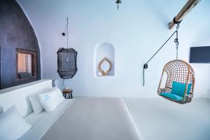 a white bedroom with a bed and a rattan basket at Sophia Luxury Suites in Imerovigli