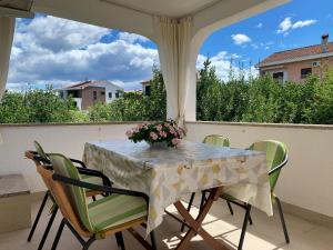 a table with chairs and a vase of flowers on a porch at Apartments Nevenka P. in Šilo