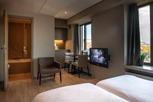 um quarto de hotel com televisão e casa de banho em Castelnou Aparthotel em Gent