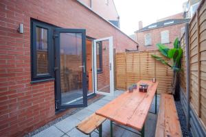 a patio with a wooden bench next to a brick building at higgihaus #3b 4 Bed Monday - Friday Whole House in Bristol