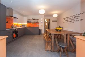 een keuken met een houten tafel en een keuken met oranje kasten bij higgihaus #3b 4 Bed Monday - Friday Whole House in Bristol