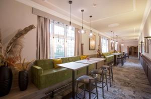 Hotel Essener Hof; Sure Hotel Collection by Best Western في إيسن: مطعم به أريكة خضراء وطاولات وكراسي