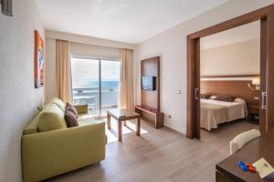 a hotel room with a couch and a bed and a window at Hotel Condesa in Port d'Alcudia