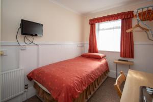 Dormitorio pequeño con cama y TV en The Rollason Hotel, en Birmingham