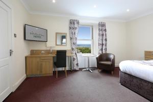 a living room with a bed, chair and a tv at Woodland Bay Hotel in Girvan