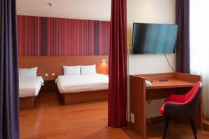 a hotel room with a bed, chair and a television at Star G Hotel München Schwabing in Munich