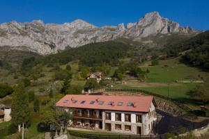 una casa en una colina con montañas en el fondo en Apartamentos Los Picos de Europa, en Colio